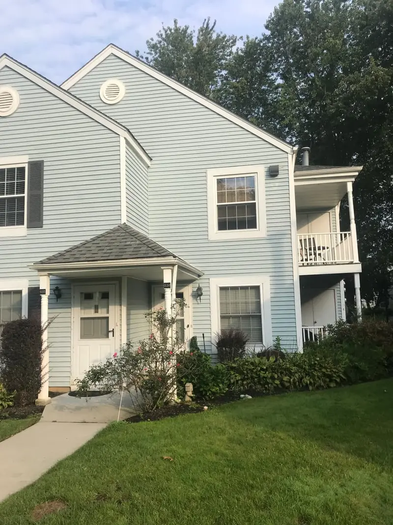 Blue-sided townhouse with a small front porch, Middle Island, NY